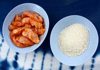 raw chicken fingers marinating in sriracha sauce and panko bread crumbs