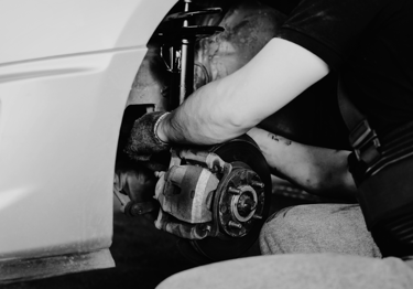 Professional mechanic performing brake pad replacement and suspension repair on a car.