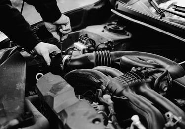 A mobile mechanic uses a screwdriver to perform car engine repair and maintenance.