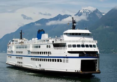 A large BC Ferries vessel sailing through scenic mountain fjords on the Pacific coast.