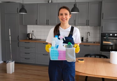 KLEAN WELL technician holding a caddy of eco-friendly cleaning supplies in a modern kitchen—Speciali