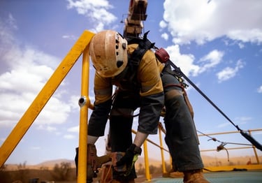 mine site worker in a harness with attached laynard working at heights