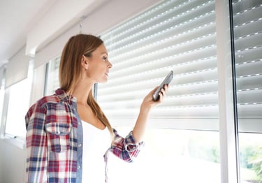 a woman holding a cell phone in front of a window