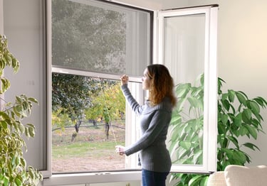 a woman standing in front of a window with a plant in the foreground