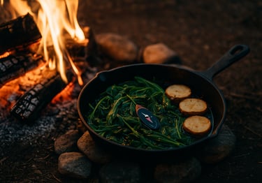 Wild greens and sliced roots cooking in skillet over fire, showing bushcraft food prep and survival meals