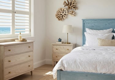 Coastal bedroom with a blue wood bed frame, light oak dresser, and coral wall decor near a window.