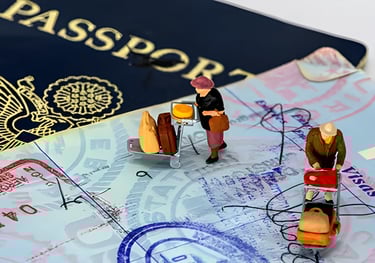 Miniature figurine pushing luggage cart on a stamped passport, illustrating visa application process