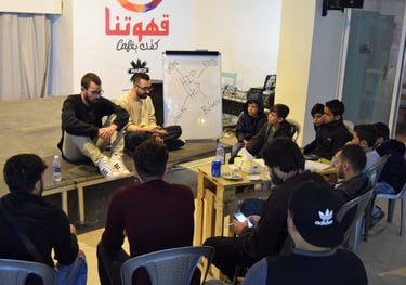 a group of people sitting around a table attending a workshop on rap music composition