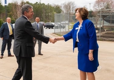 a man and woman shaking hands in front of a fence
