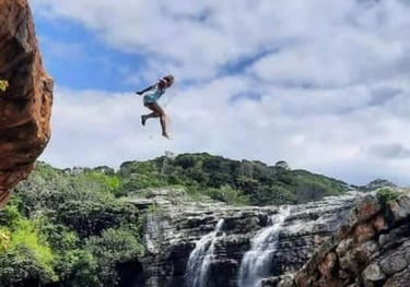 Lady jumping out of Baboon cave with Strandlooper falls behind her
