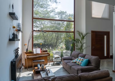 fotografía inmobiliaria quito ecuador tumbaco  gran sala de estar con muebles, piano y un gran ventanal con luz natural