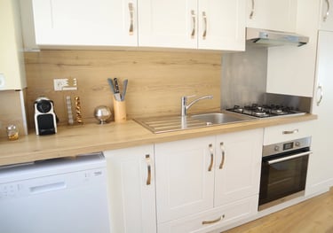 Cuisine équipée moderne avec four, plaques, lave-vaisselle et plan de travail en bois