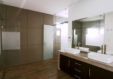 baño de recámara principal con espacios independientes y cancelería en cristal