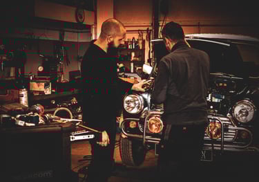 two men working on a mini cooper  in  garage ; deux hommes travaille sur le moteur d'une mini cooper
