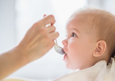 a baby is gets food with a spoon