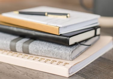 a stack of books and a pen on a table