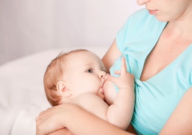 a woman breastfeeding a baby in a blue dress
