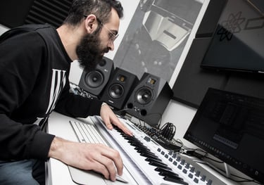 a man in a black shirt is playing a midi keyboard in a studio producing music in lebanon