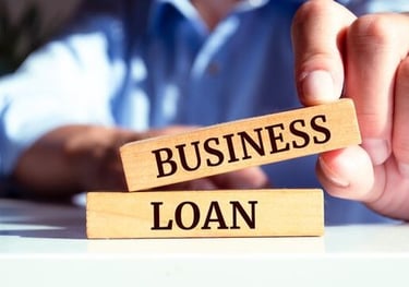 a man holding a wooden block with the words business loan dream inc