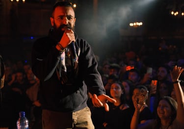 a man in a black jacket and a microphone in front of a crowd, rapper, beatlalipos, concert, rap, 