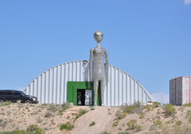a statue of a alien standing in front of a building