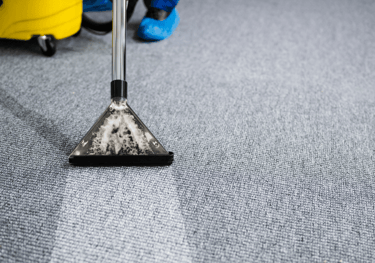 a person cleaning a carpet with a broom