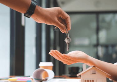a person handing a keychaik to a house