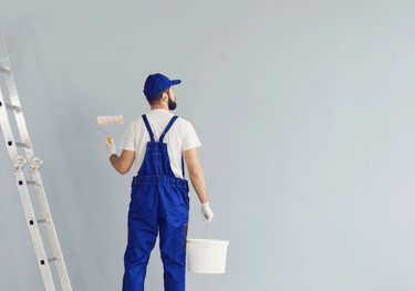 a man in blue overalls and a bucket hat, holding a paint roller