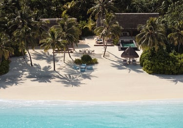 a beach with a beach chair and palm trees, One and Only Reethi Rah