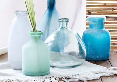 a table with galss vases of different coastal and sea colors