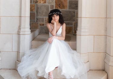quinceanera in a white dress sitting on a stone stepstone