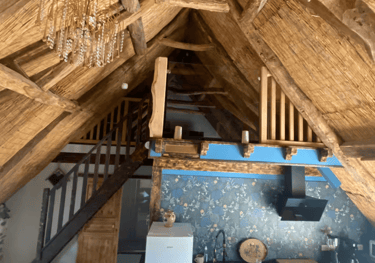 Livingroom sous les combles et le toit en chaume, mezzanine et escalier