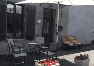 Entrée du gîte avec la table, les chaises sous un parasol