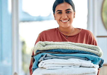 a woman holding a stack of folded towels