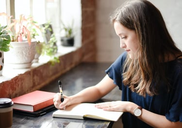 Young woman writing at a desk, symbolizing personalized guidance in crafting compelling SoPs and LOR