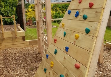 Oak and Larch play structure in a garden with climbing net, climbing wall and monkey bars