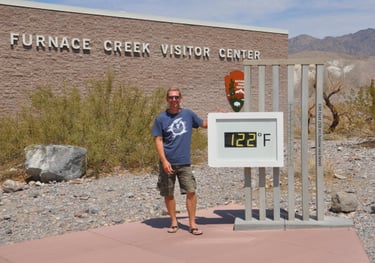 a man standing in front of a sign that says furnace furnace creek, death valley