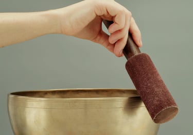 a person holding a singing bowl with a hand holding a small object