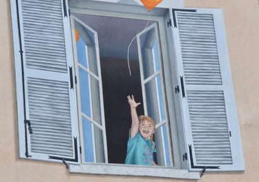 Détail d'un trompe-l'oeil sur façade à Moirans-en-Montagne: Une fillette à une fenêtre au 1er étage.