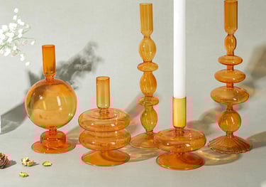 a group of candles and tapered glass candle and pillar holder