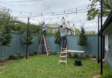 landscape lighting technicians installing patio string lights with poles