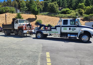 Redwood Towing medium duty tow truck towing a large dump truck.