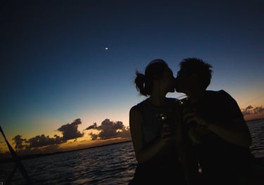 The photo shows a couple kissing on a sunset boat tour.