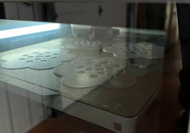 the interior of a 3D printer showing 4 flower frog vase toppers being made from natural PLA plastic