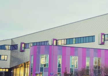 a modern academy school with sharp lines in a triangular shape with purple ground floor.