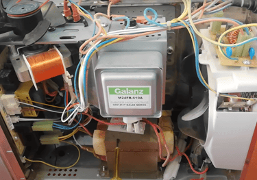 a picture showing internal component of a microwave. Magnetron and transformer is shown