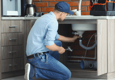 a man in a blue shirt and jeans is fixing a sink