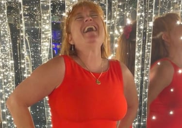 Picture of Teva in a red cocktail dress on Resilient Lady, Virgin Voyages cruise, enjoying a laugh 