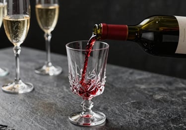 A close-up photograph of a bottle of red wine being poured into a crystal glass. The setting is a Brazilian high-end bar at night, with dark slate grey textures and champagne gold highlights on the glassware.