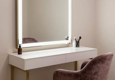 An elegant mirror station in a professional beauty studio in a North American / NYC Hispanic neighborhood, featuring muted plum chair and soft almond white accents.